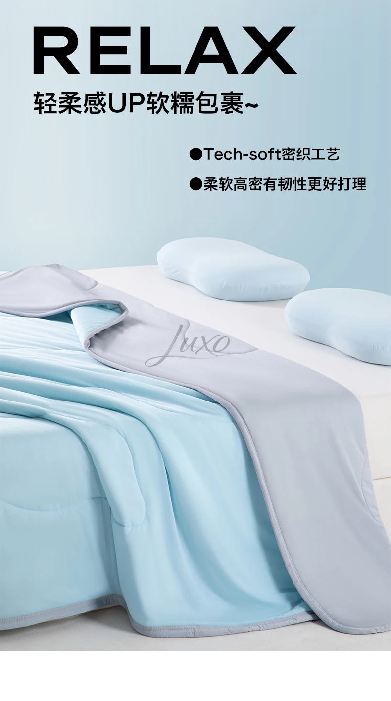 A light blue and gray ice silk blanket is shown folded on a white surface with soft pillows nearby.