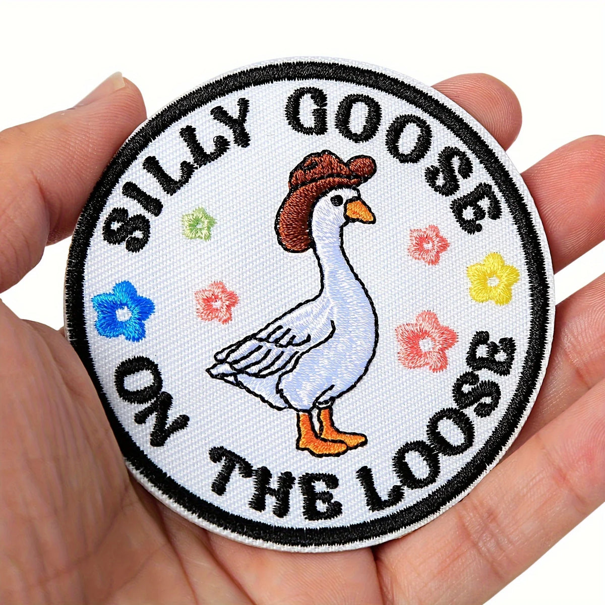 Embroidered hook and loop patch featuring a white goose on the loose design surrounded by floral elements.