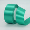 Roll of teal satin craft ribbon with a white core