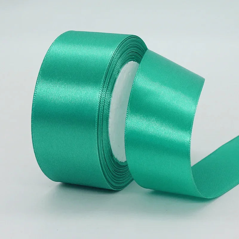 Roll of teal satin craft ribbon with a white core