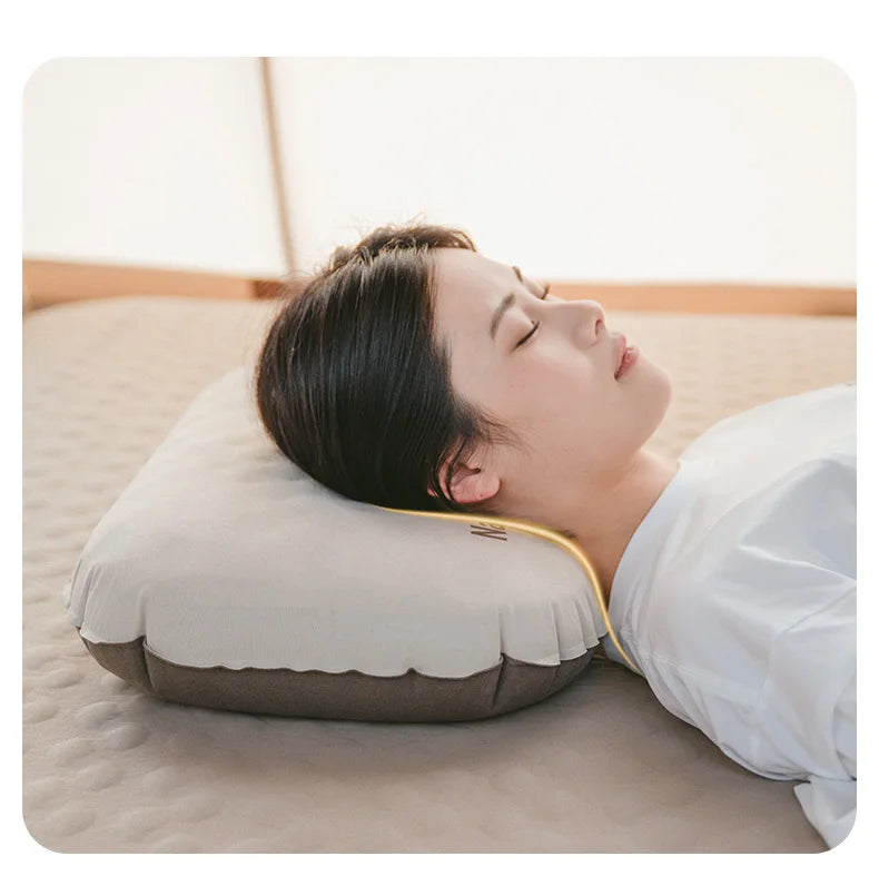 A person is resting their head on a beige inflatable camping pillow indoors.