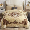 A beige weighted blanket with intricate brown floral patterns is displayed on a bed.