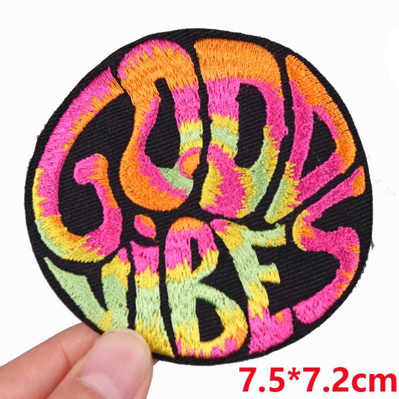 A round black embroidered patch with colorful text that reads GOOD VIBES