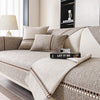 A beige linen sofa cover with decorative piping and cushions displayed in a bright living room setting.
