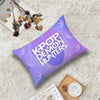 A purple cushion cover featuring the text KPOP DEMON HUNTERS on a white background, placed on a fluffy surface.