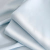 A stack of light blue ultra-breathable ice silk cooling bed sheets folded and draped.