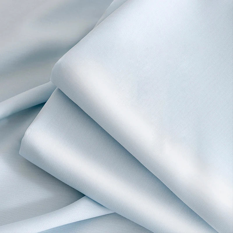A stack of light blue ultra-breathable ice silk cooling bed sheets folded and draped.