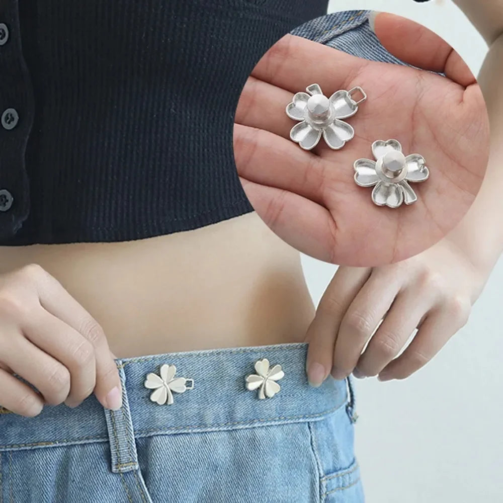Silver adjustable button clips used to tighten the waist of a denim garment.