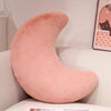A soft, pink moon-shaped throw pillow resting on a white surface.
