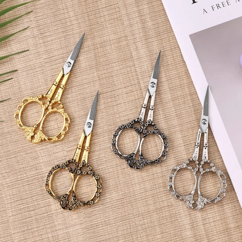 A set of four crafting scissors in gold and silver finishes displayed on a light brown background.
