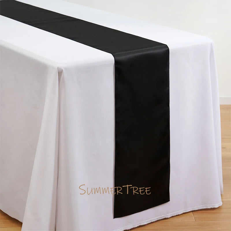 Elegant satin black table runner draped across a white tablecloth.