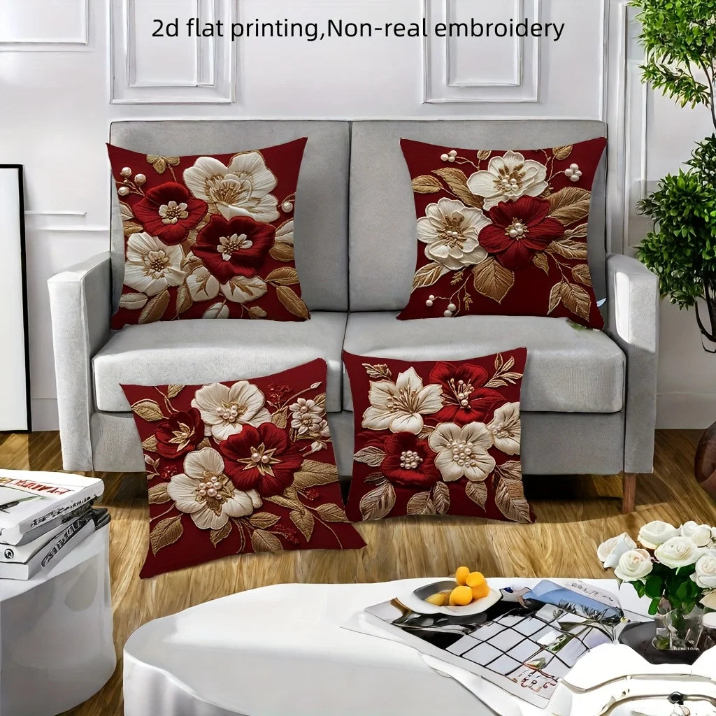 A set of red and cream floral embroidered pillow covers displayed on a gray sofa.