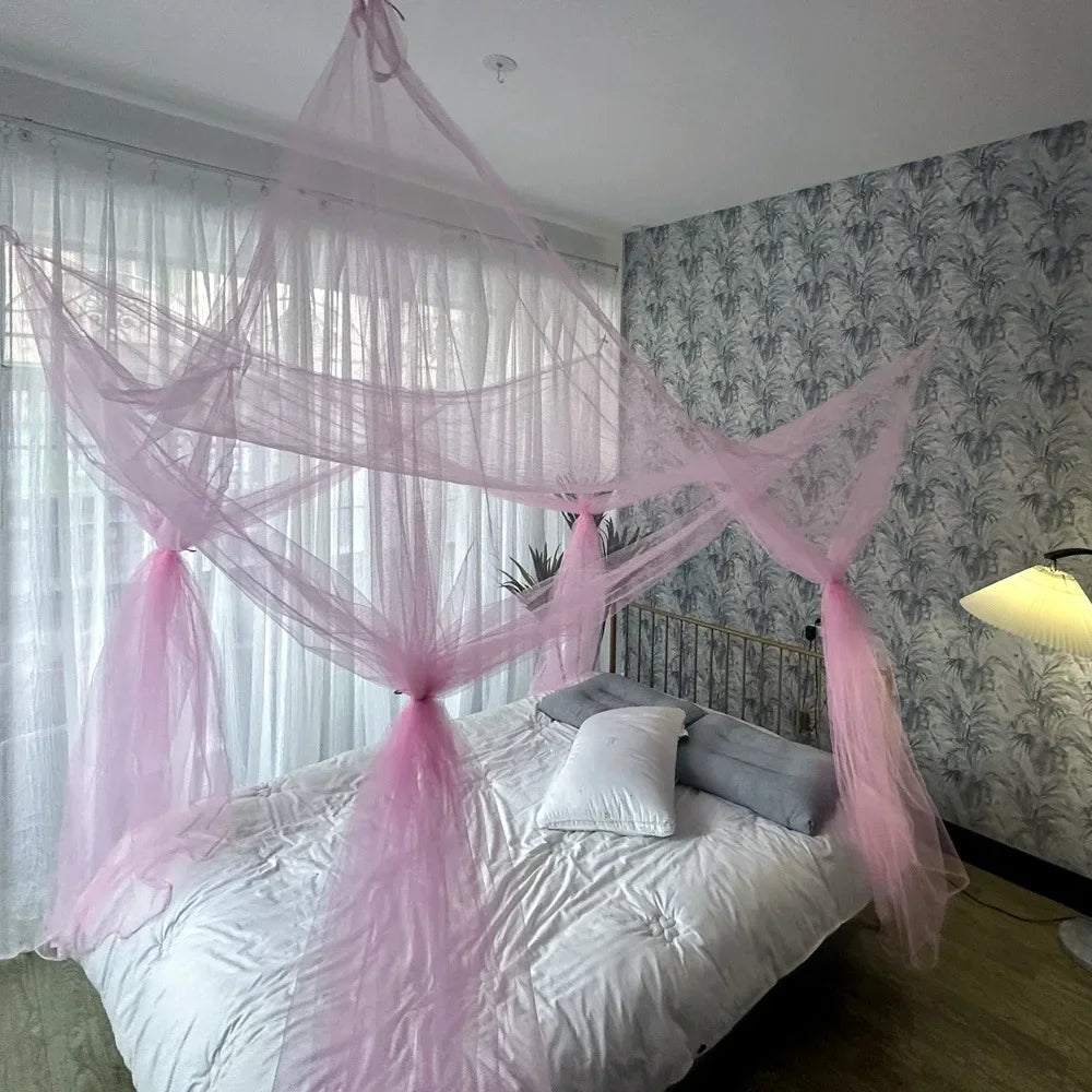 A large four-door mosquito net draped over a bed in a room with gray patterned wallpaper and sheer white curtains.