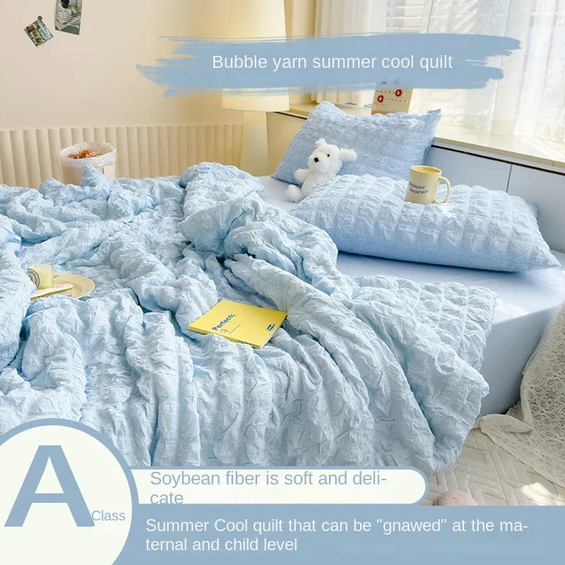 Light blue bubble yarn summer cool quilt with a white stuffed animal on a bed