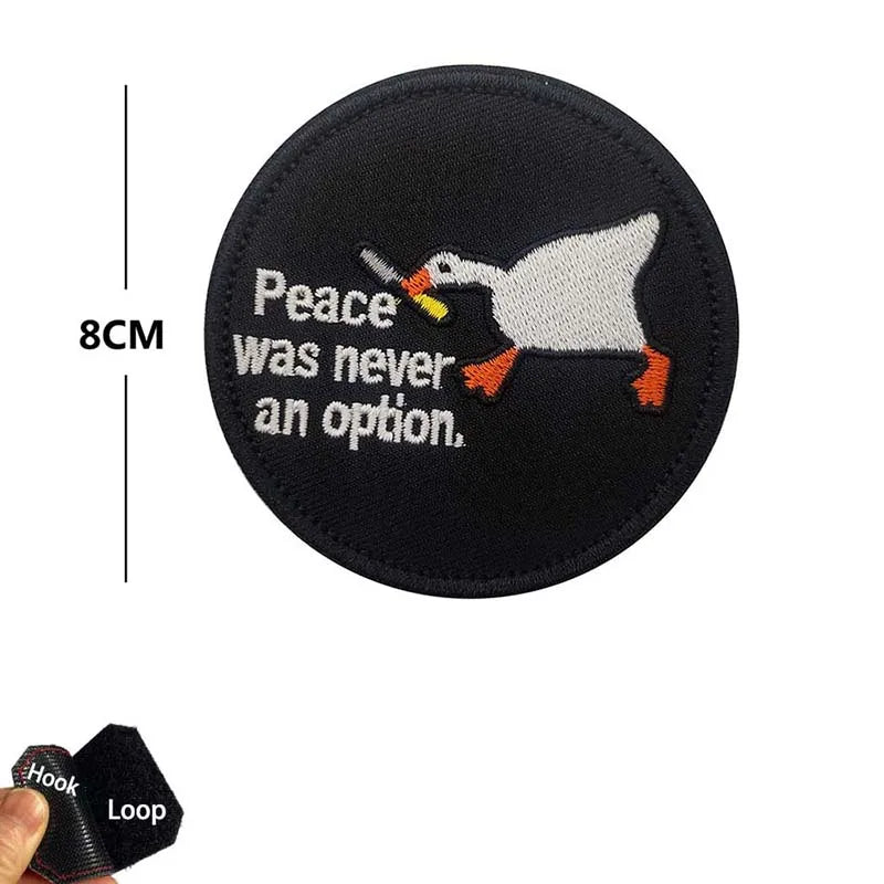 Black embroidered patch featuring a white bird with yellow beak and orange feet, depicting the text Peace was never an option