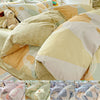 A close-up of a beige and olive green cotton duvet and pillow set featuring geometric patterns.