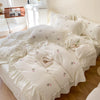 White duvet cover set with pink embroidered roses on a bed