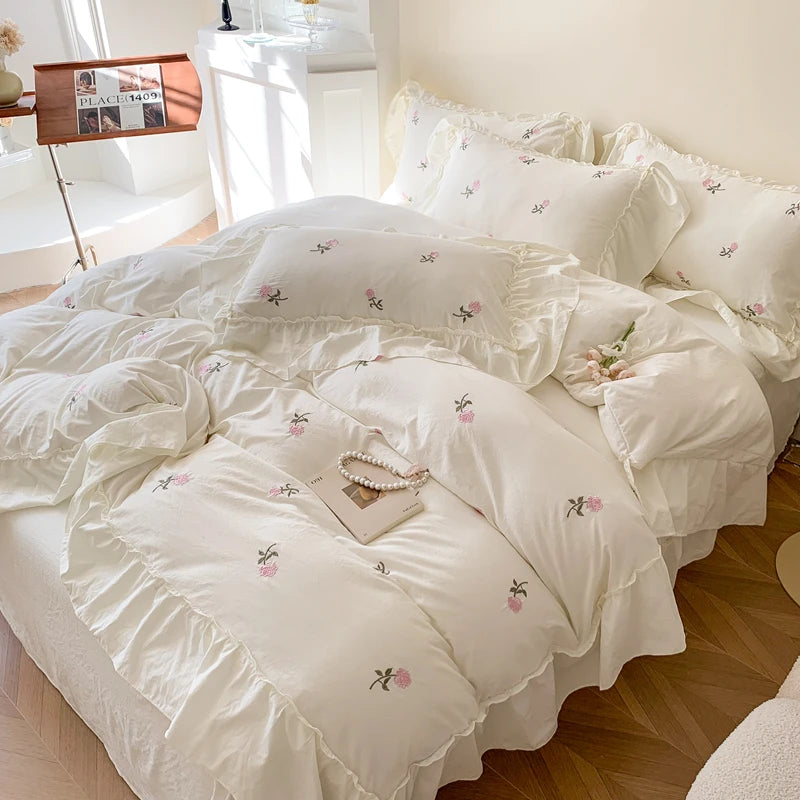 White duvet cover set with pink embroidered roses on a bed