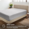 A light gray fitted bed sheet on a wooden bed frame with a white wall background.