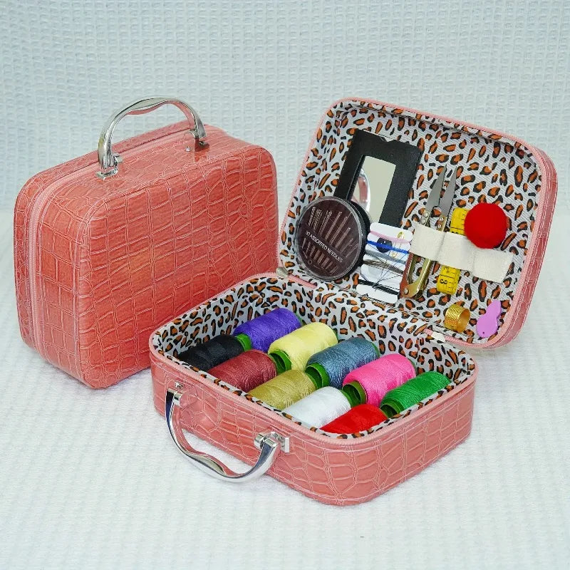 A pink portable sewing kit box with an open lid showing various needles, thread, and tools.