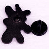 A black enamel brooch shaped like a stylized, irregular figure with a pin mechanism.