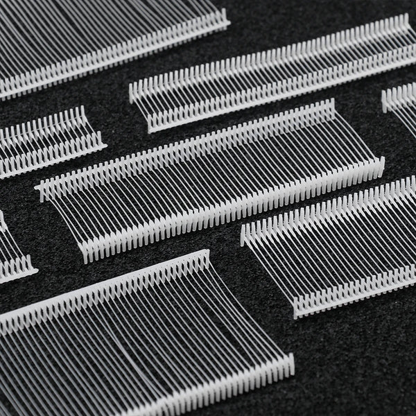 Close-up view of precision plastic tagging barbs for labels on a dark surface.