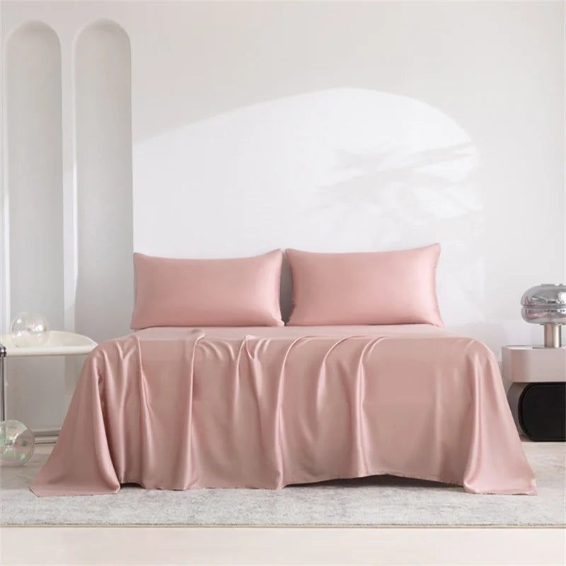 A pink luxury organic bamboo bed sheet set draped on a bed in a bright, minimalist room.