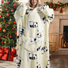 A woman models a cream-colored sherpa fleece oversized blanket hoodie featuring black panda patterns in a festive holiday set