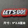 Red embroidered Let's Go badge with white text on a dark gray background