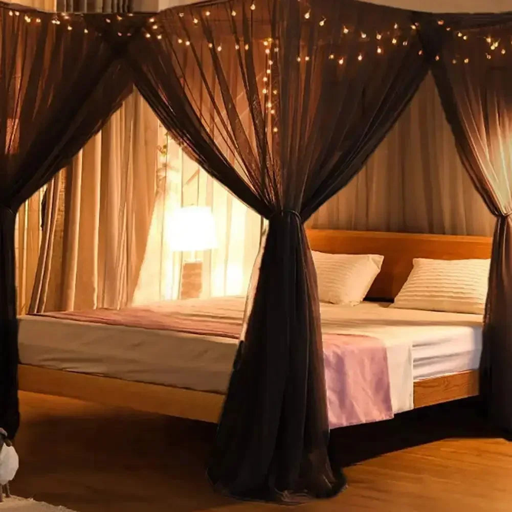A queen size mosquito net canopy draped with sheer fabric over a wooden bed.