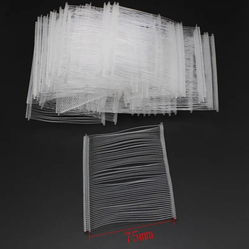 A collection of white precision plastic tagging barbs or wires laid out on a dark surface.