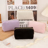 A collection of velvet cosmetic storage pouches in lavender, cream, and pink are displayed in front of a box.