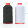 A spool of black heavy duty nylon sewing thread with a red base and a spool of white heavy duty nylon sewing thread with a re