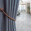 A close-up of a gray pleated curtain with a copper magnetic rope tieback.