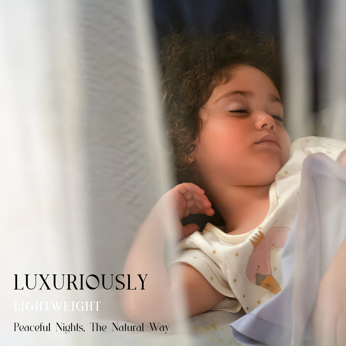 A baby is sleeping peacefully under a sheer white mosquito net canopy.