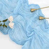 Light blue sheer gauze fabric draped with white roses and gold metal accents for table decor