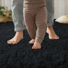 A pair of legs wearing brown polka dot leggings standing on a black plush area rug.