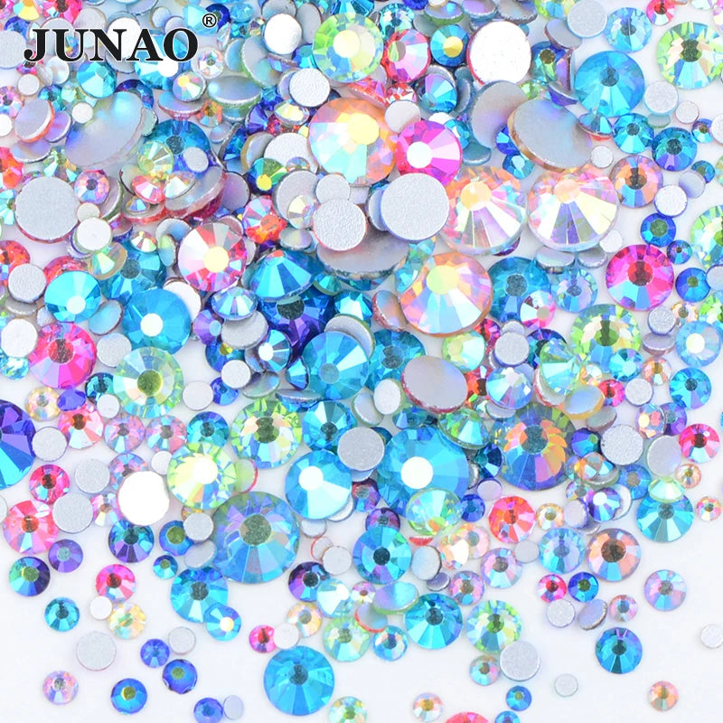 A pile of clear glass rhinestones in various colors including blue, pink, and green for DIY crafts