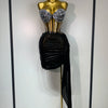 A gold mannequin displays a sparkly diamond two-piece performance set featuring embellished top and a black draped skirt.