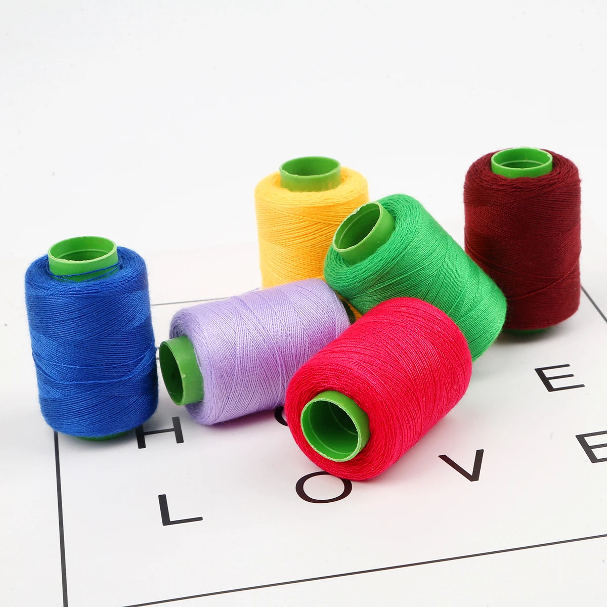 A collection of hand-dyed sewing threads in various colors including blue, purple, green, yellow, and red spools.