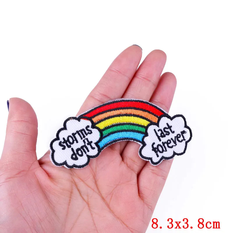 Rainbow embroidered patch with the text storms don't and last forever on a hand