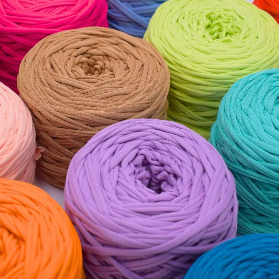 A vibrant collection of skeins of craft yarn in various shades including pink, orange, green, blue, and purple.