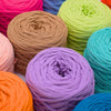 A vibrant collection of skeins of craft yarn in various shades including pink, orange, green, purple, and blue.