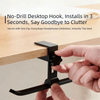 A hand installs a black desk hook onto a wooden table surface.