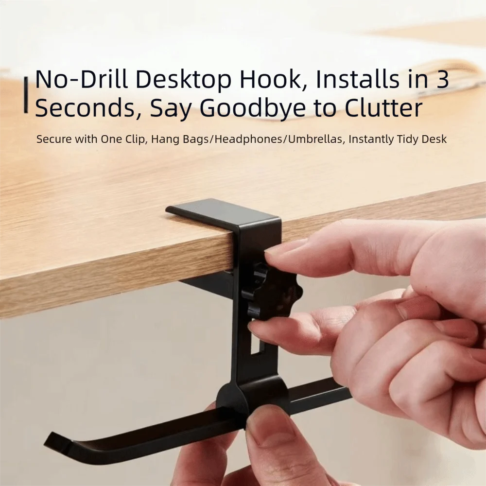 A hand installs a black desk hook onto a wooden table surface.