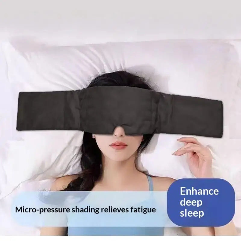 A woman is wearing a black micro-pressure shading sleep mask while lying in bed.