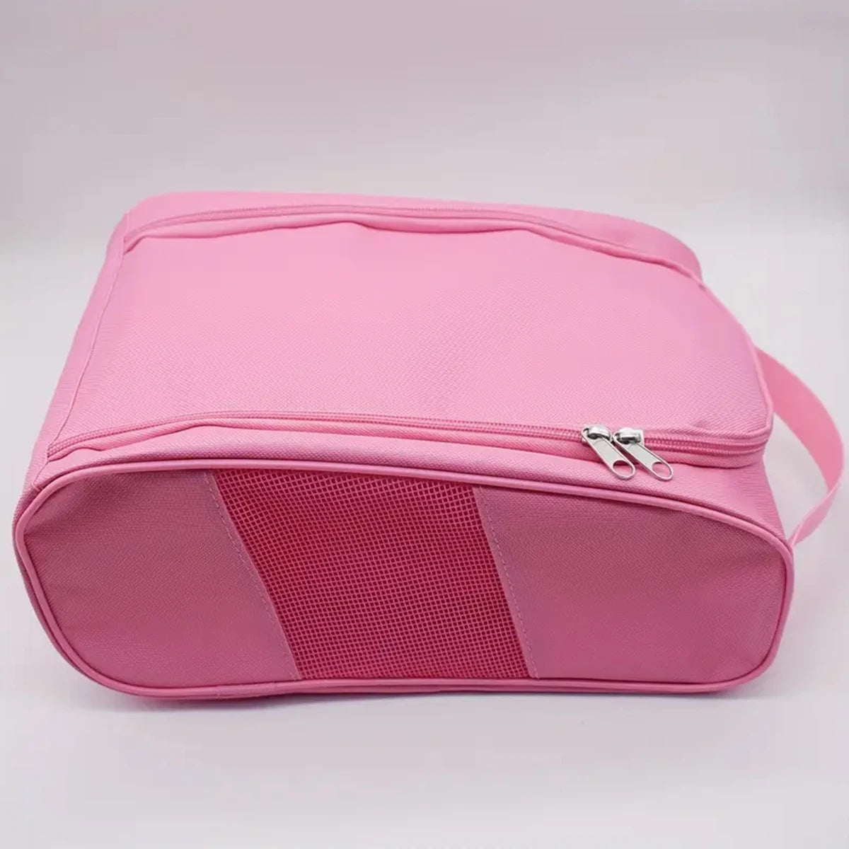 A pink portable shoe carrier bag with a mesh panel on the front.