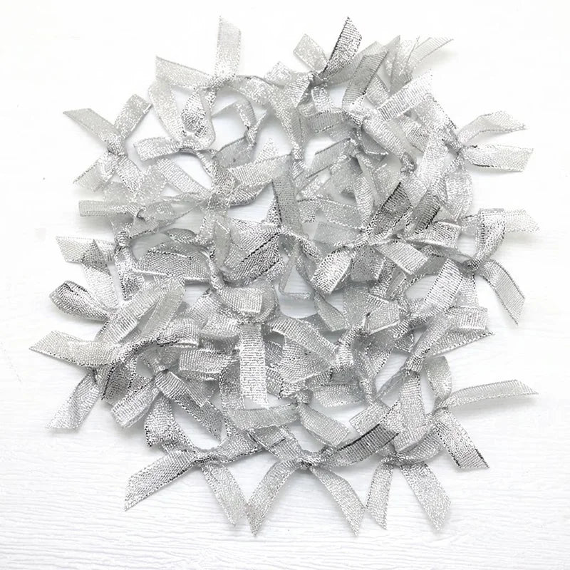 A pile of small silver satin ribbon bows for crafts and decor.