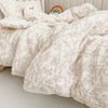 A soft, cream-colored muslin blanket with a delicate floral print is folded on a light surface.
