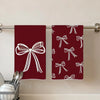 Two deep red kitchen towels with white bow patterns hanging on a metal rod.